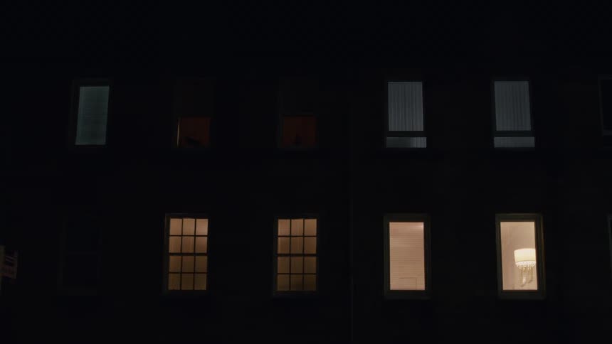 An apartment building at night, with several lit windows
