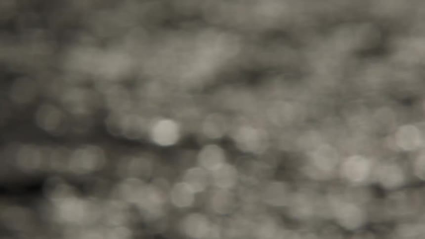 An abstract, soft-focus shot of shimmering light creating a bokeh effect on the surface of moving water