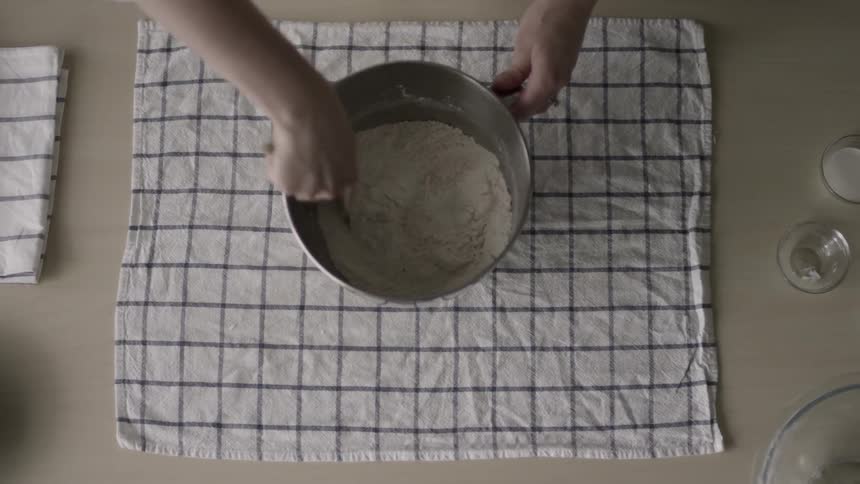 A person mixes flour in a bowl