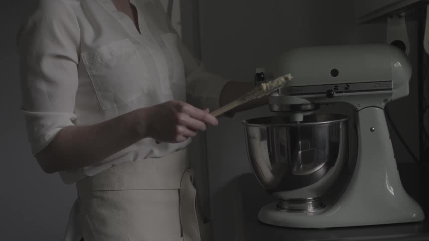 A woman uses a stand mixer in the kitchen