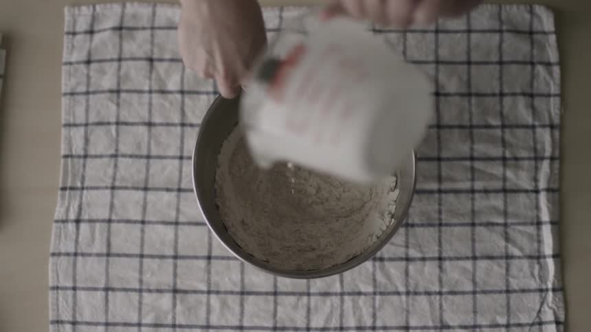 Woman pours milk into a bowl and continues to mix the ingredients