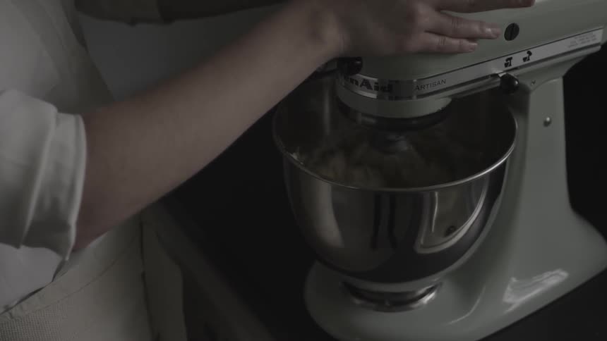 A woman is using a stand mixer