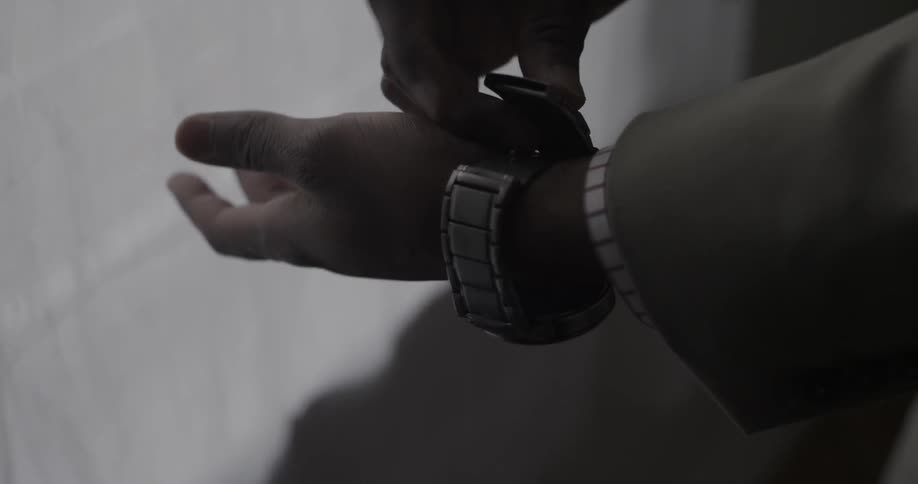 A man puts on a watch and clips it shut