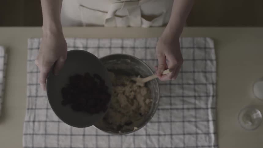 A woman adds chocolate chips to cookie batter