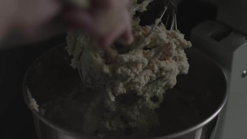Person scrapes batter off a whisk with a spoon
