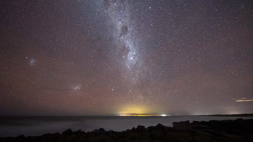 A stunning timelapse of the Milky Way and stars rotating in the night sky over a misty ocean and rocky coastline