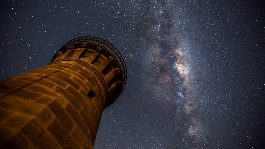 A stunning time-lapse from a low angle captures the Milky Way galaxy moving across the starry night sky behind an ancient stone tower