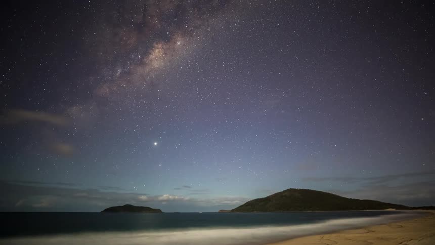 A beautiful time-lapse of the Milky Way galaxy moving across the starry night sky over a serene beach and ocean