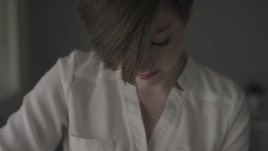 A woman is working on something in a dark room