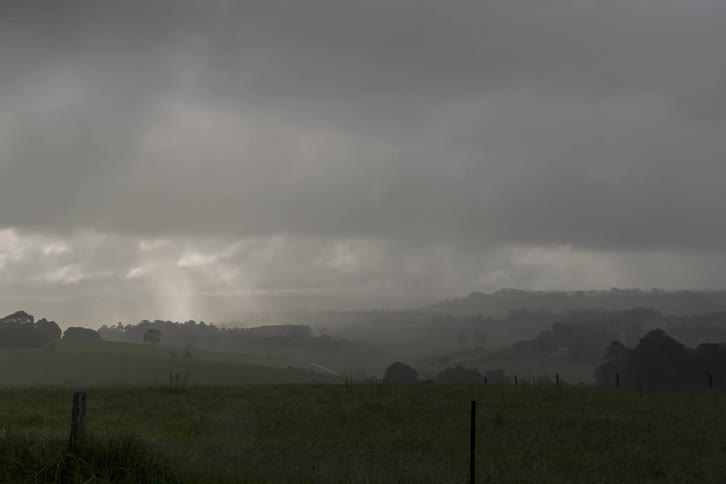 A time-lapse of stormy clouds and sunbeams moving across a lush, green, hilly landscape