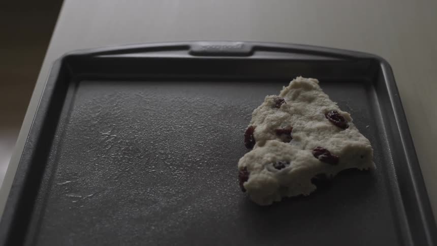 A person placing raw cookie dough on a baking sheet