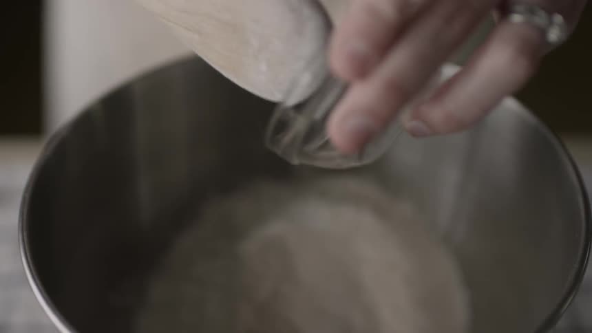A bowl of spices is spooned into a bowl