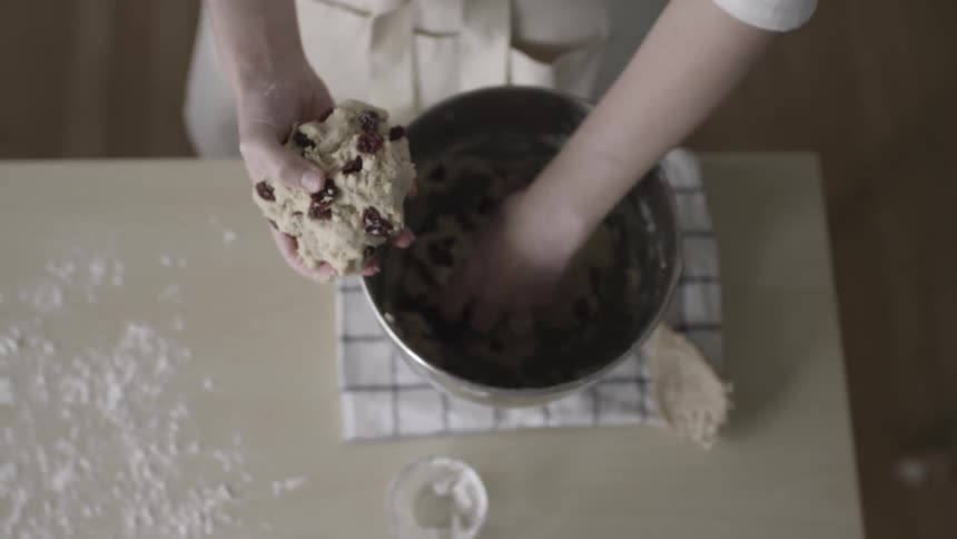 Woman takes cookie batter out of a metal bowl