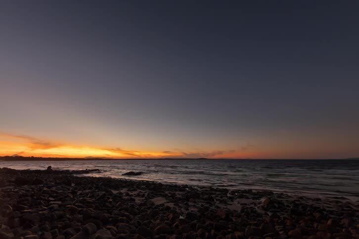 A stunning day-to-night timelapse shows the sun setting over the ocean, revealing a beautiful starry sky above a rocky coastline