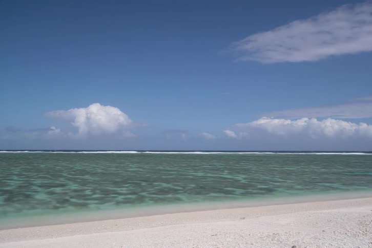 A tranquil and beautiful tropical beach with clear turquoise water and a white sand shore under a blue sky
