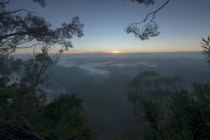 A beautiful time-lapse of a golden sunrise over a sea of fog in a lush green mountain valley
