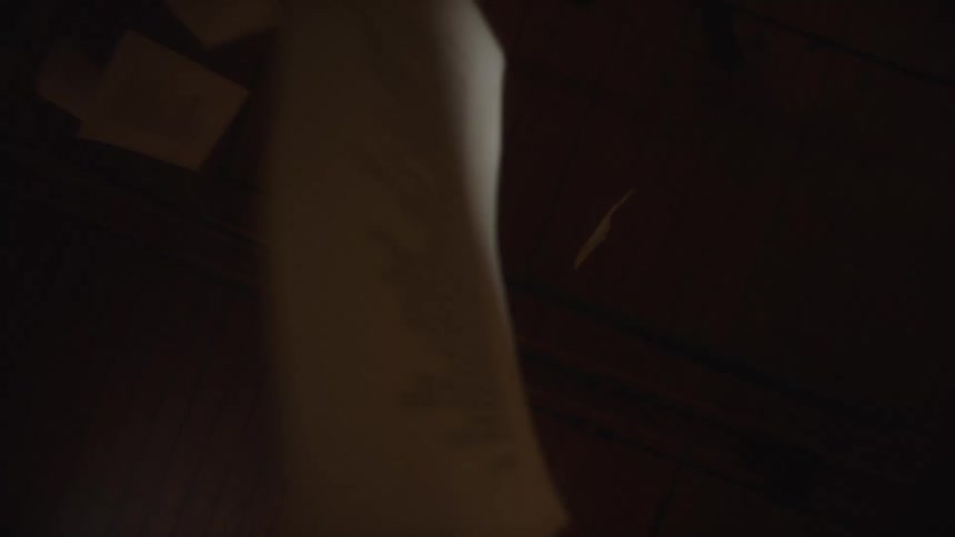 Dramatic low-angle shot of white papers falling slowly against a dark wooden ceiling