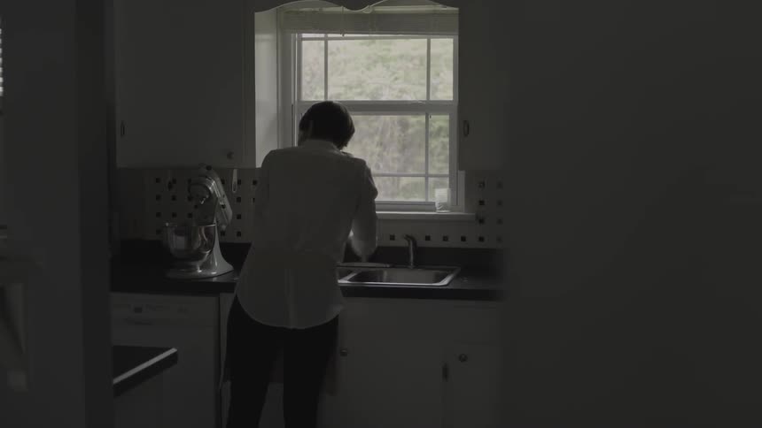 A woman washes her hands in the kitchen sink