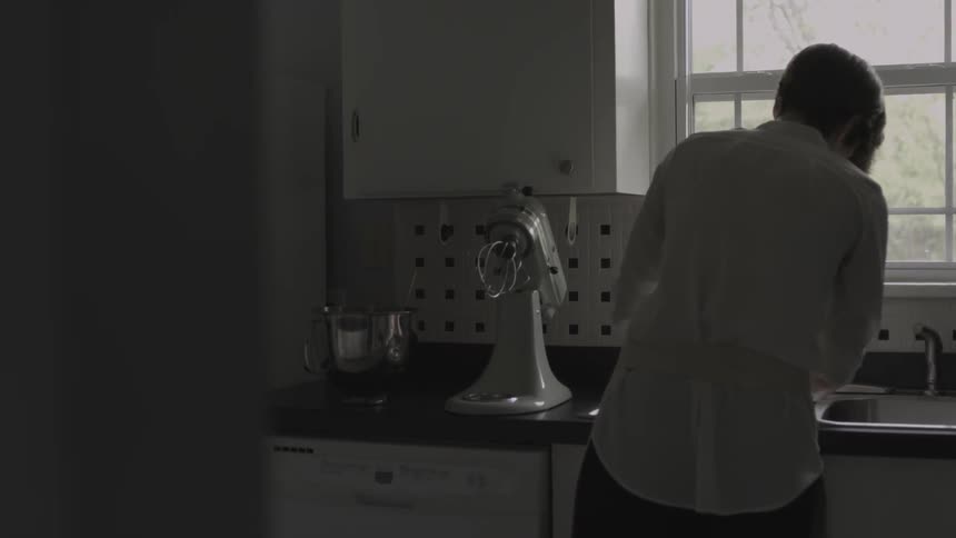 A woman is washing up dishes at a kitchen sink