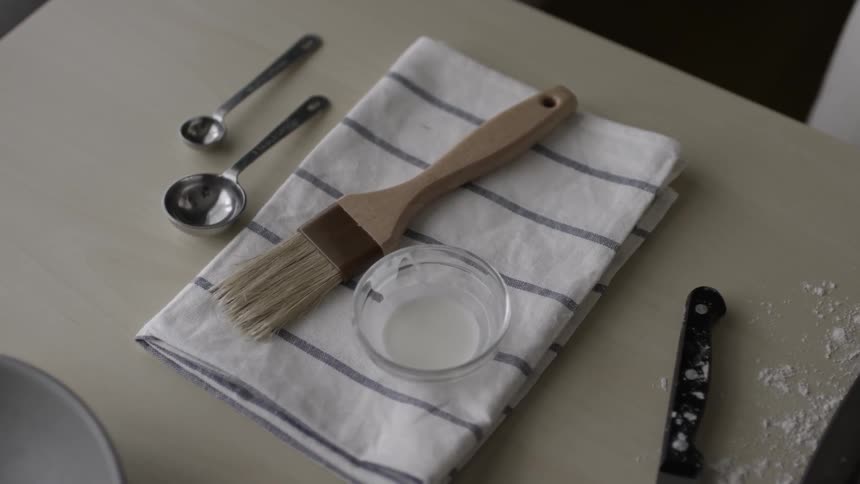 A paintbrush and some paint sit on a towel