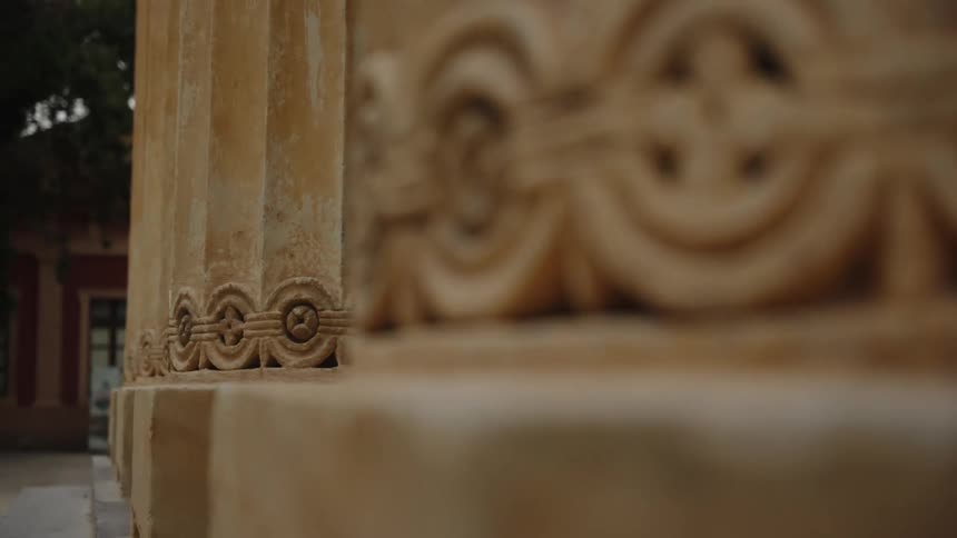 A shallow focus close-up shot of intricate carvings on the base of an ancient stone column