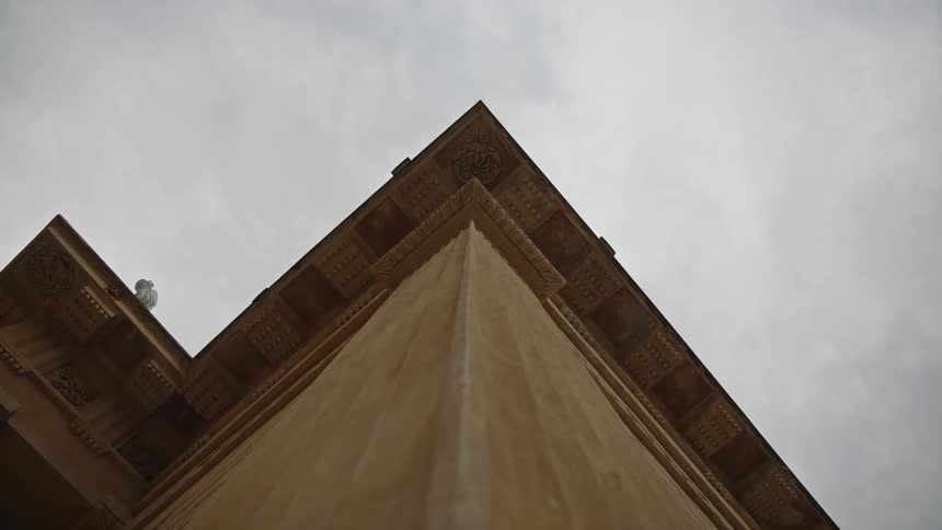 A symmetrical low-angle shot of a classic building's corner under a grey, cloudy sky
