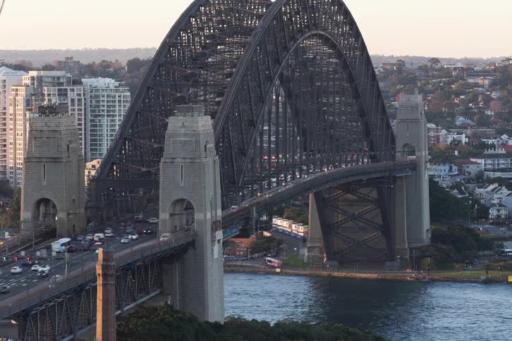 Time-lapse of heavy traffic on the iconic Sydney Harbour Bridge as boats and a train pass by