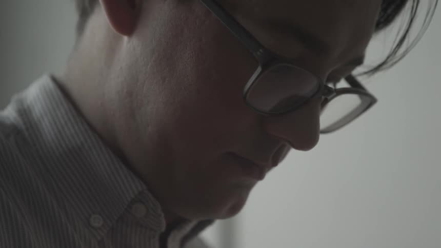 A wearing glasses is looking down at something