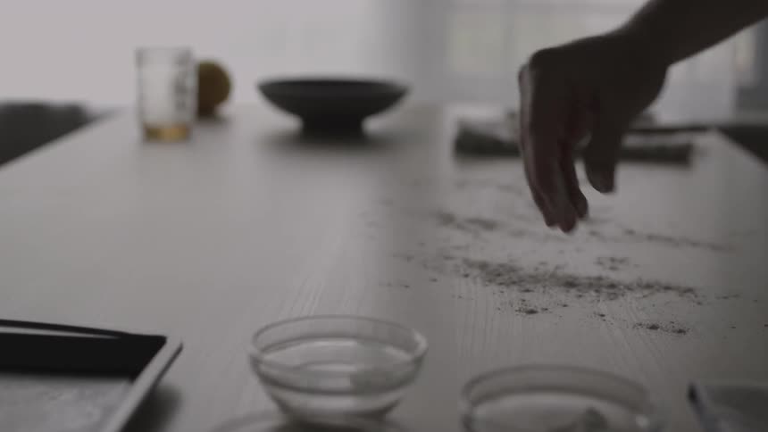 A woman sprinkles flour onto a kitchen counter