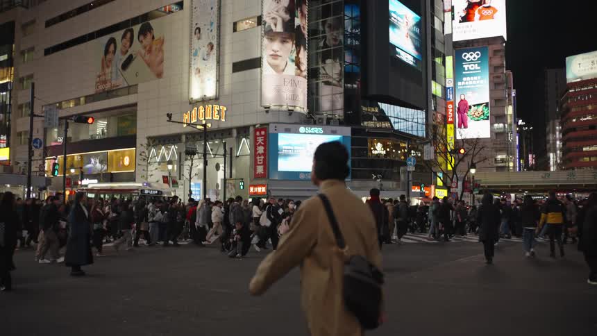 Pedestrians fill the street at the iconic Shibuya Crossing intersection in Tokyo, Japan, illuminated by vibrant city lights