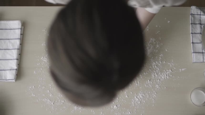 A woman puts down two pieces of cookie dough on the table