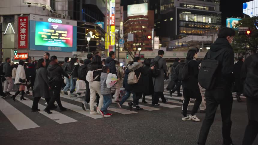Mesmerizing slow motion shot of a diverse crowd of pedestrians crossing the famous Shibuya Scramble in Tokyo at night