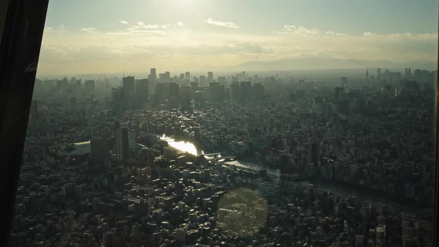 A majestic aerial view of the vast Tokyo cityscape at sunset with a river reflecting the golden sunlight