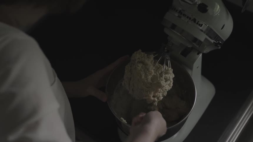 A woman scoops batter out of a mixer