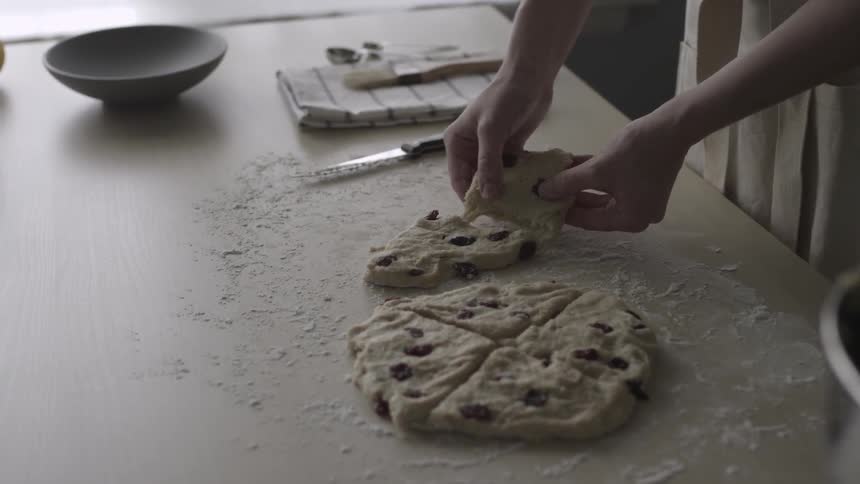 A person breaks pieces of dough and puts them on a pan