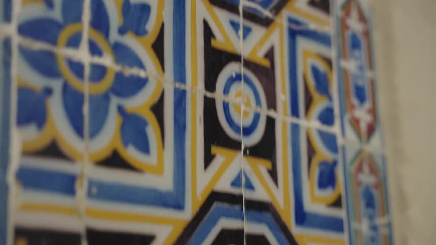 A close-up, slow-moving shot reveals the intricate and colorful geometric patterns of traditional antique ceramic tiles on a wall