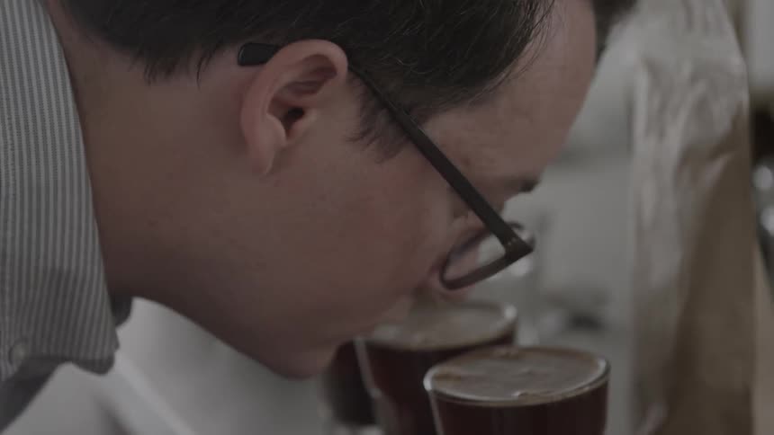 A man smells a row of glasses of coffee