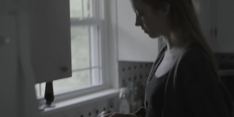 A woman gets mugs from a kitchen cupboard