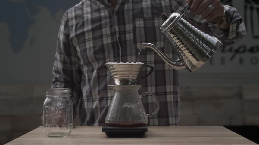 Man pours water over coffee grounds