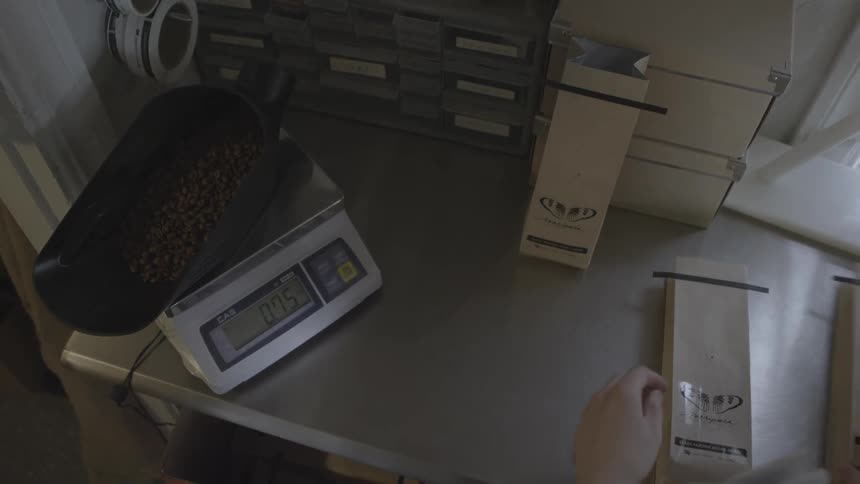 A man empties a bag of coffee beans onto a scale