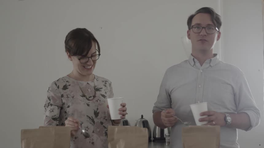 A man and woman are holding coffee cups and having a conversation