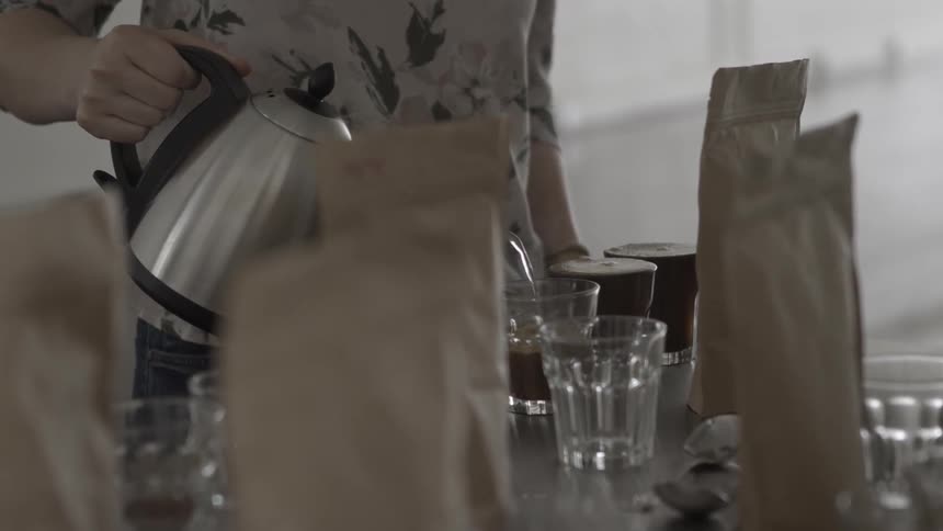 Woman pouring water into cup of coffee beans in a shop