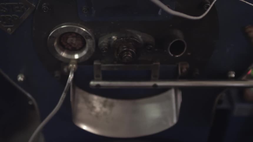 A person checks on roasting coffee beans