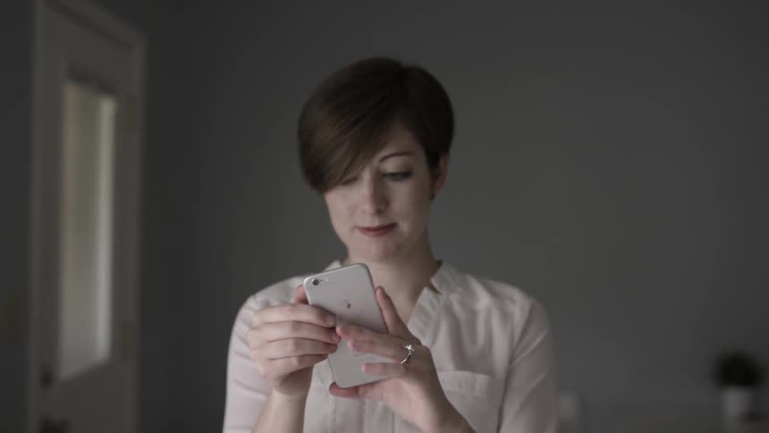 A woman uses her phone smiling