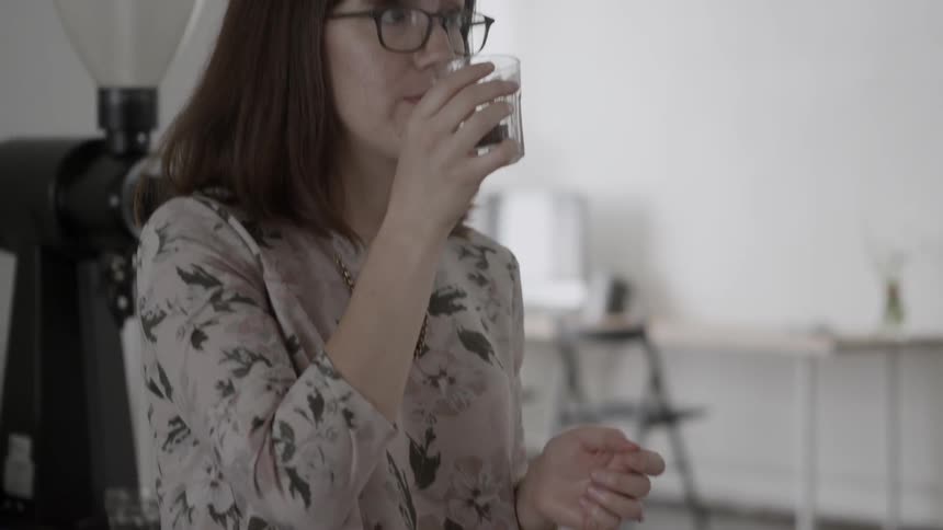 Woman in a kitchen drinks from a crystal glass