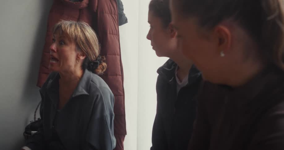 A female coach gives an impassioned speech to her team of young female athletes in the locker room