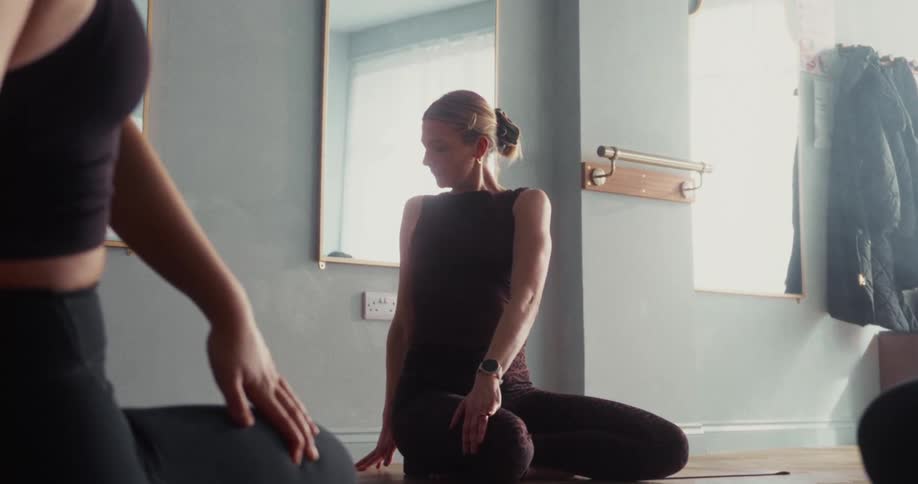 A woman holds a deep seated twist during a sun-drenched yoga class in a tranquil studio