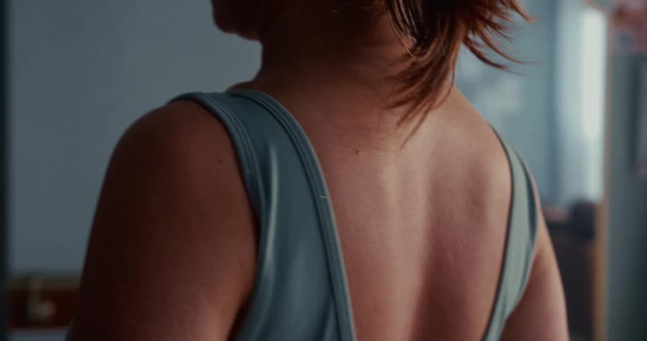 Over-the-shoulder slow motion close-up of a woman's back and shoulders in a tank top