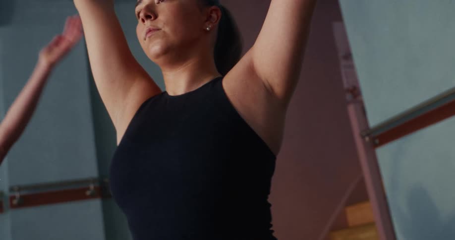 Close-up of a focused woman in a black top holding a yoga pose during a class in slow motion