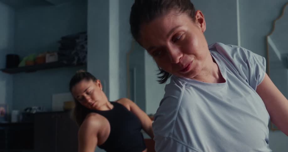 A determined woman smiles through the discomfort of a deep side bend stretch during her yoga practice